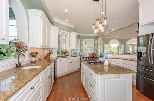 kitchen featuring white cabinets, decorative backsplash, stainless steel appliances, crown molding, and a sink