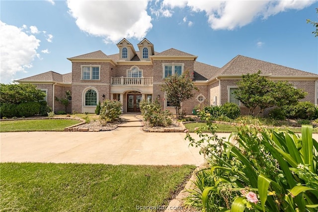 mediterranean / spanish-style house featuring a front yard, french doors, and a balcony