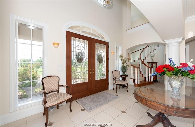 tiled entryway with ornate columns, french doors, and a towering ceiling