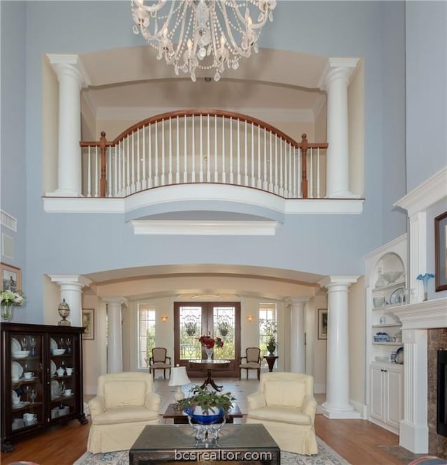 living room featuring hardwood / wood-style flooring, a high ceiling, a tile fireplace, and an inviting chandelier