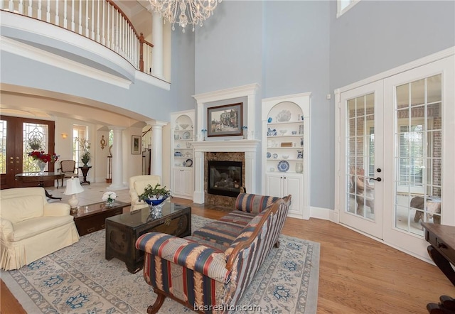 living room featuring decorative columns, french doors, a towering ceiling, and plenty of natural light