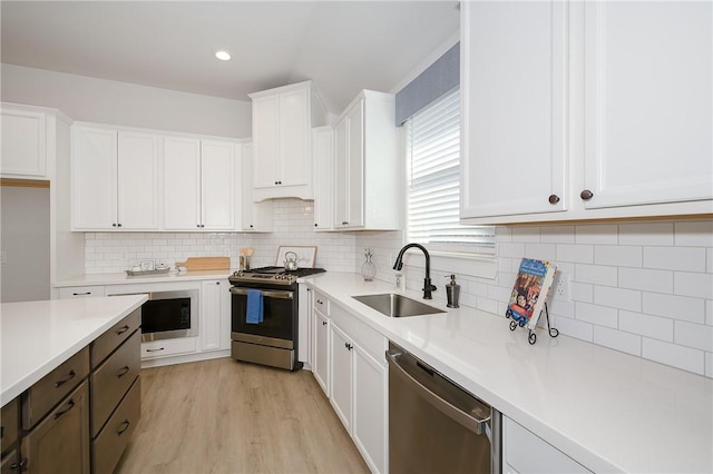 kitchen with light hardwood / wood-style floors, decorative backsplash, sink, stainless steel appliances, and white cabinets