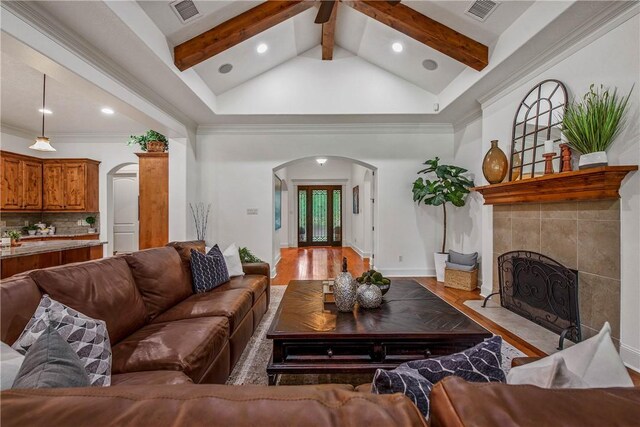 3281 Toltec Trl, College Station, TX 77845 - living room featuring visible vents, arched walkways, a tile fireplace, and beamed ceiling