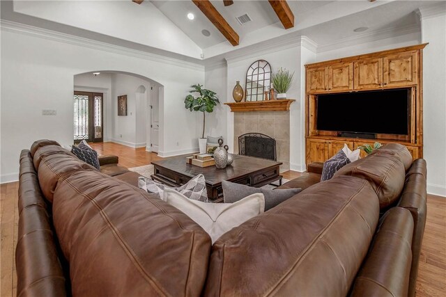 3281 Toltec Trl, College Station, TX 77845 - living room with a fireplace, light wood-style floors, arched walkways, vaulted ceiling with beams, and visible vents