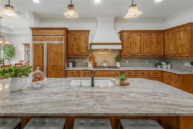 3281 Toltec Trl, College Station, TX 77845 - kitchen featuring paneled refrigerator, brown cabinetry, a kitchen bar, a sink, and custom exhaust hood