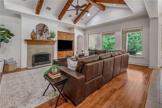 3281 Toltec Trl, College Station, TX 77845 - living area with a ceiling fan, visible vents, a tiled fireplace, arched walkways, and vaulted ceiling with beams