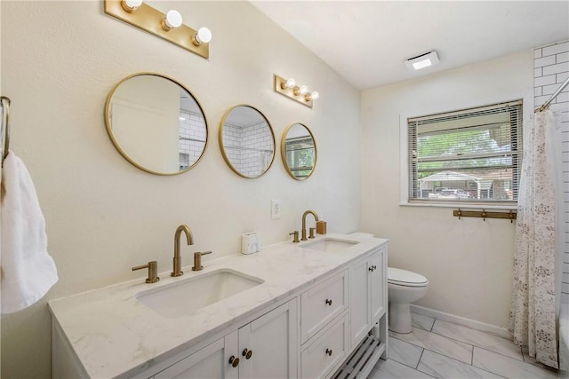 full bathroom with marble finish floor, double vanity, toilet, and a sink