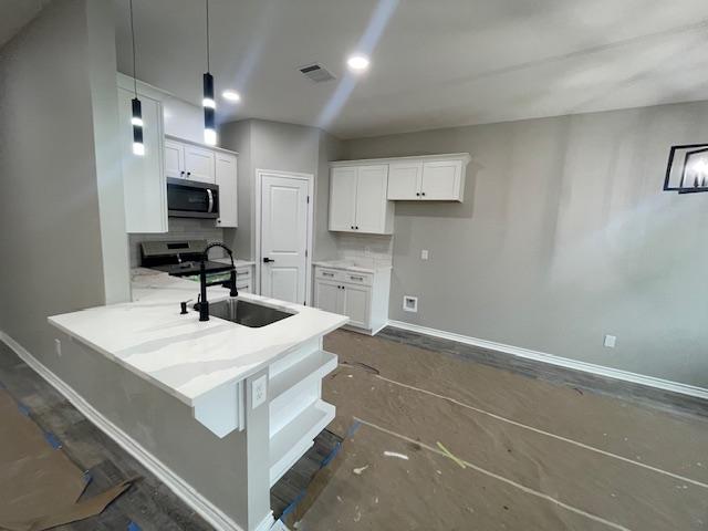 kitchen with white cabinetry, sink, hanging light fixtures, and appliances with stainless steel finishes