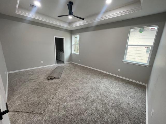 carpeted empty room featuring a raised ceiling, crown molding, and ceiling fan