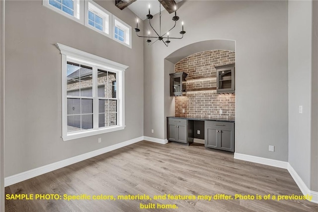 4760 Coral River Rd, College Station, TX 77845 - bar featuring an inviting chandelier, light wood-style floors, baseboards, and high vaulted ceiling