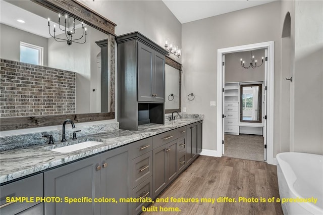 4760 Coral River Rd, College Station, TX 77845 - bathroom featuring a sink, wood finished floors, a chandelier, and a soaking tub