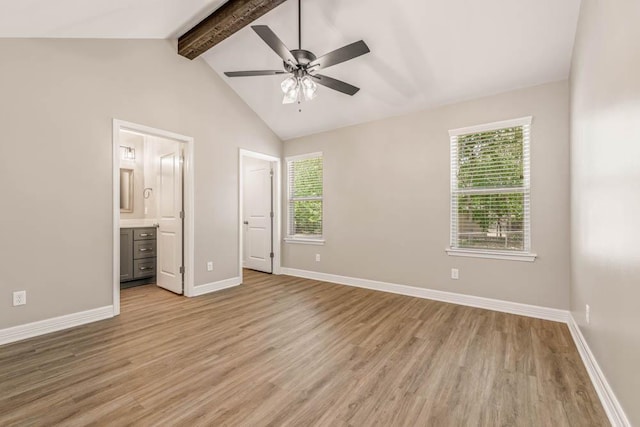 unfurnished bedroom featuring ceiling fan, ensuite bathroom, light hardwood / wood-style flooring, and vaulted ceiling with beams