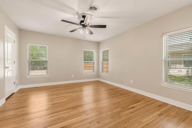 spare room featuring ceiling fan, light hardwood / wood-style flooring, and a healthy amount of sunlight