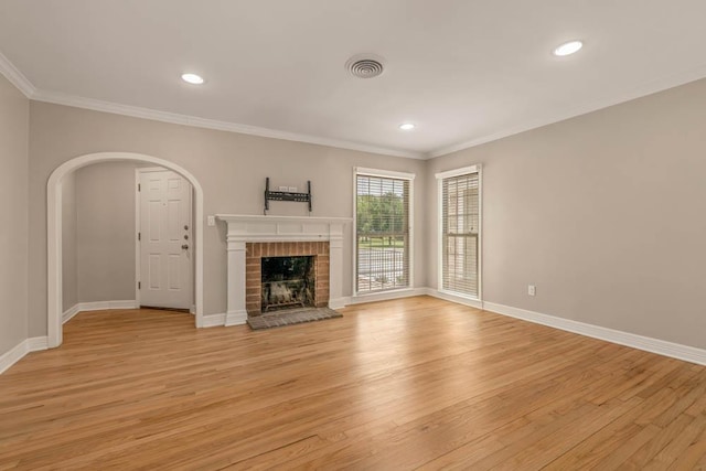 unfurnished living room featuring a brick fireplace, light hardwood / wood-style flooring, and ornamental molding