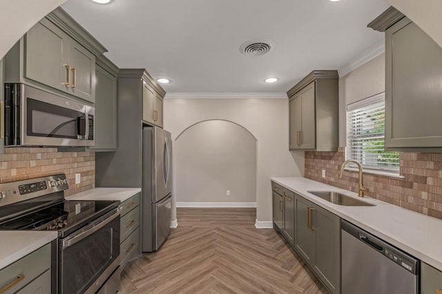 kitchen with stainless steel appliances, gray cabinetry, light parquet flooring, crown molding, and sink