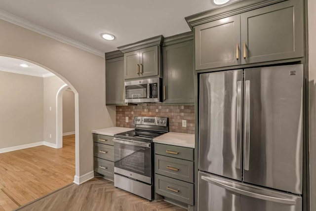 kitchen featuring appliances with stainless steel finishes, gray cabinetry, crown molding, and tasteful backsplash