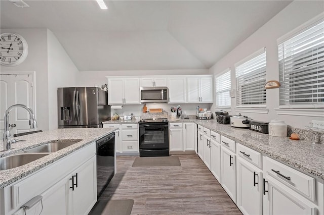 kitchen with plenty of natural light, black appliances, lofted ceiling, and light hardwood / wood-style flooring