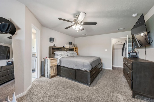 carpeted bedroom with a walk in closet, a closet, and ceiling fan