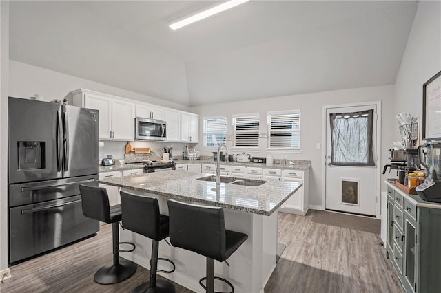 kitchen featuring white cabinetry, a center island, lofted ceiling, and appliances with stainless steel finishes