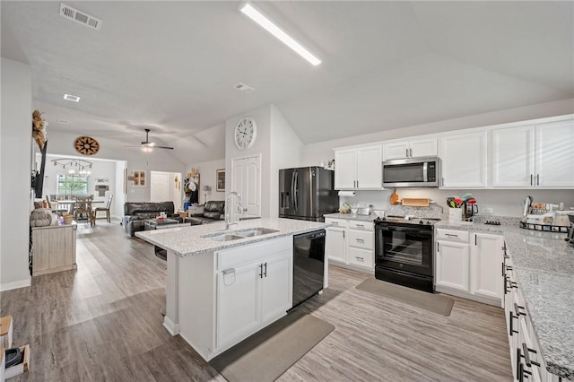 kitchen featuring black appliances, white cabinetry, lofted ceiling, and sink