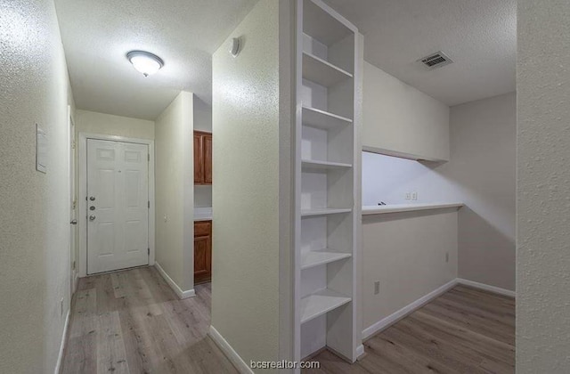 hall with light hardwood / wood-style floors and a textured ceiling