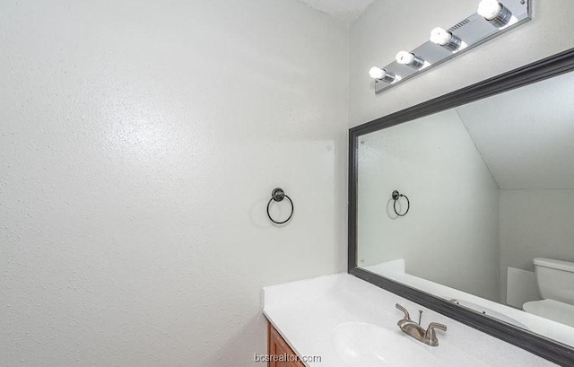 bathroom with vanity, vaulted ceiling, and toilet