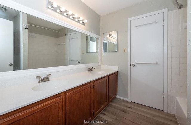 bathroom featuring hardwood / wood-style flooring, vanity, and tiled shower / bath