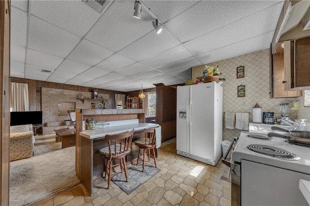 kitchen with pendant lighting, white appliances, a drop ceiling, and a breakfast bar area