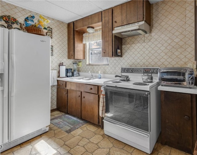 kitchen with white appliances, a paneled ceiling, and sink