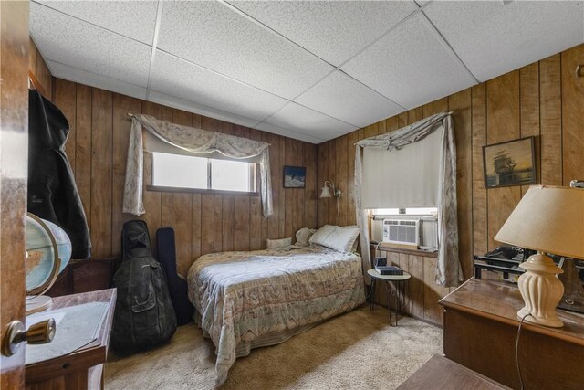 bedroom featuring light carpet, a drop ceiling, cooling unit, and wood walls