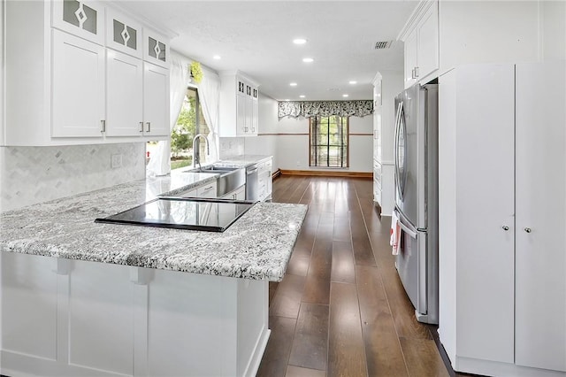 kitchen with white cabinets, light stone countertops, kitchen peninsula, and dark wood-type flooring