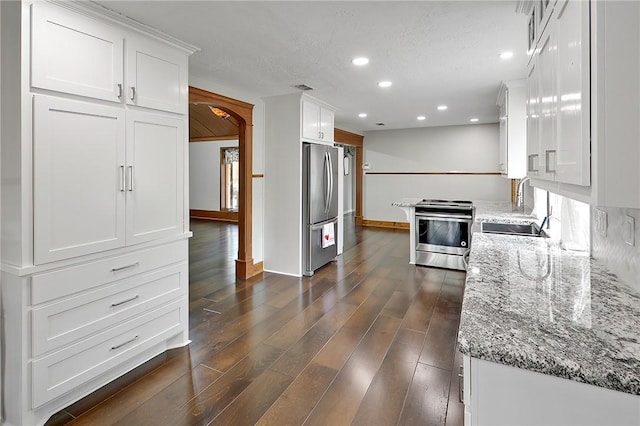 kitchen with sink, light stone counters, dark hardwood / wood-style flooring, white cabinets, and appliances with stainless steel finishes