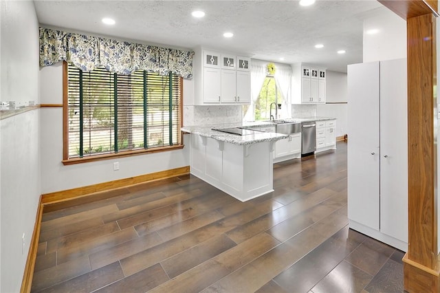 kitchen with kitchen peninsula, a breakfast bar, white cabinetry, and dishwasher