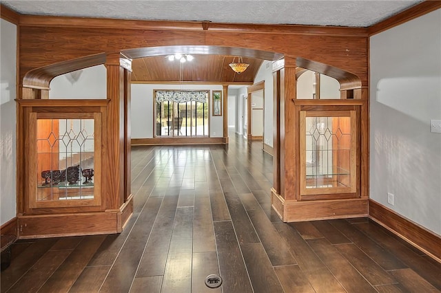 hallway featuring dark hardwood / wood-style flooring, ornamental molding, a textured ceiling, and decorative columns