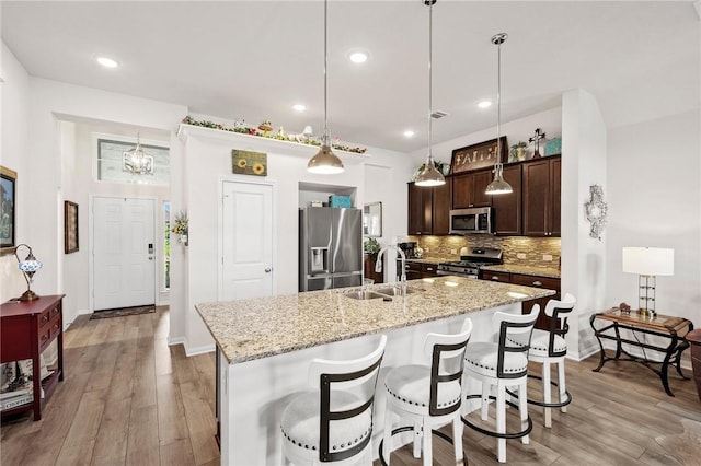 7902 Putter Place Ct, Navasota, TX 77868 - kitchen featuring appliances with stainless steel finishes, dark brown cabinets, light wood-style floors, backsplash, and recessed lighting