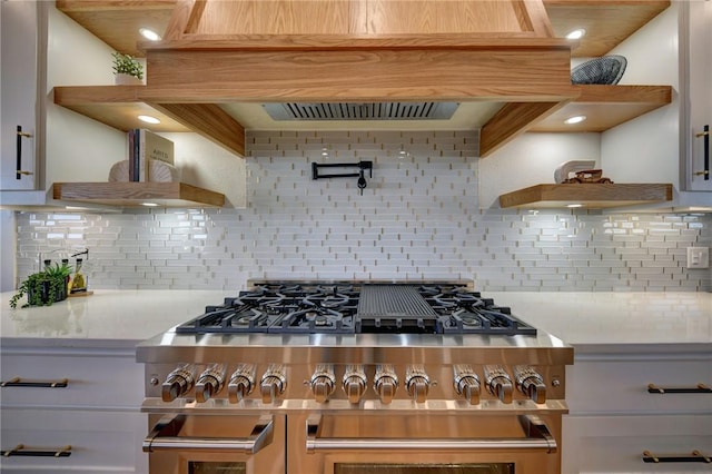 kitchen featuring white cabinetry, light stone countertops, range with two ovens, and backsplash