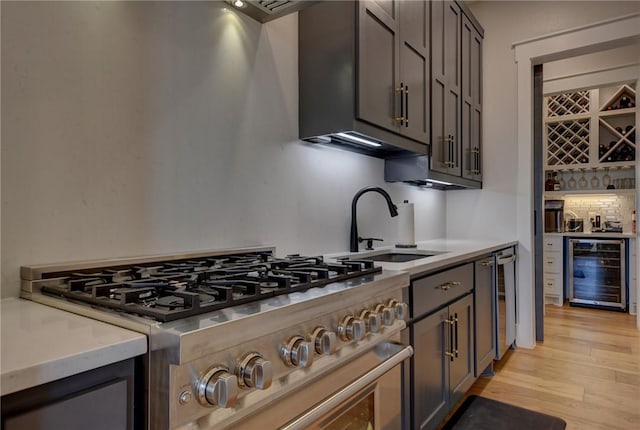 kitchen with gray cabinets, sink, wine cooler, light hardwood / wood-style floors, and stainless steel range oven