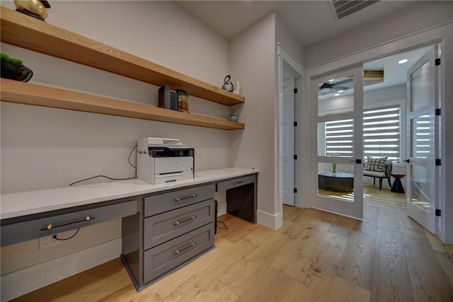 office space featuring french doors, ceiling fan, built in desk, and light wood-type flooring