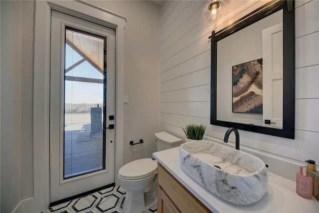 bathroom with vanity, wooden walls, and toilet