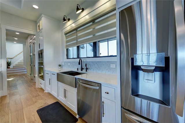 kitchen featuring stainless steel appliances, white cabinetry, sink, and backsplash