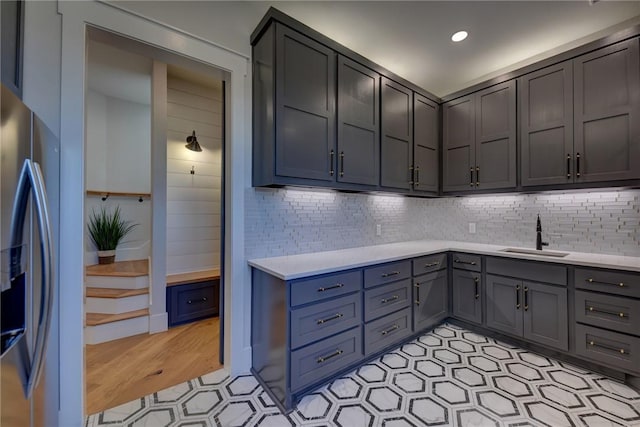 kitchen featuring backsplash, stainless steel fridge, sink, and gray cabinetry