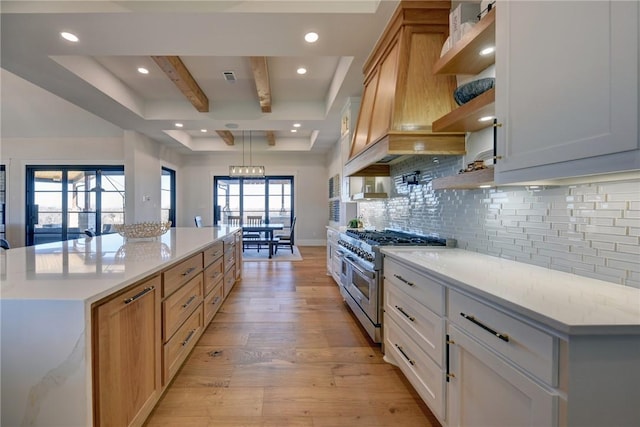 kitchen with a kitchen island, light hardwood / wood-style floors, range with two ovens, and white cabinets