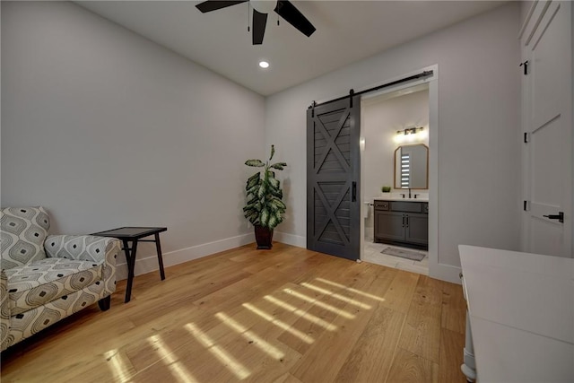 living area featuring light hardwood / wood-style floors, a barn door, and ceiling fan