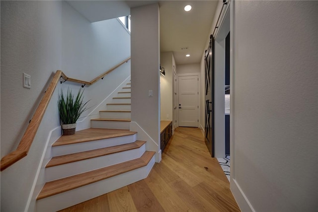 staircase with a barn door and hardwood / wood-style floors