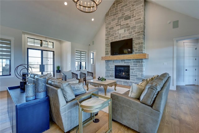 living room featuring a stone fireplace, light wood-type flooring, high vaulted ceiling, and french doors