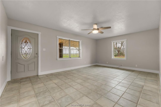 entryway with ceiling fan, light tile patterned flooring, and a textured ceiling