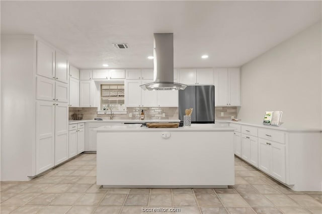 kitchen featuring white cabinets, stainless steel fridge, and island range hood