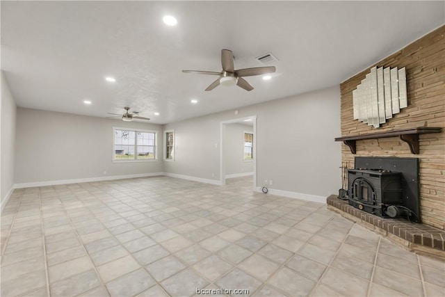 unfurnished living room with a wood stove and ceiling fan