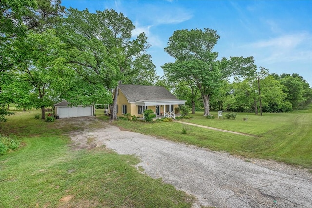 view of front of home featuring an outbuilding, a front lawn, a detached garage, and view of wooded area