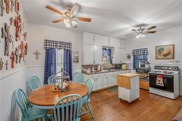 kitchen with electric stove, ceiling fan, a sink, butcher block countertops, and tasteful backsplash